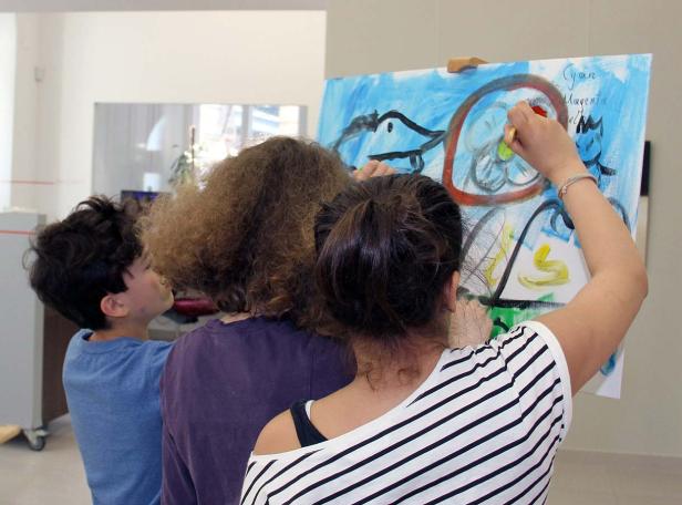 Eine Gruppe von Personen malt gemeinsam auf einer Leinwand.