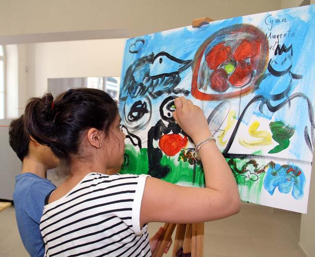 Ein Mädchen malt ein abstraktes Bild auf einer Staffelei.