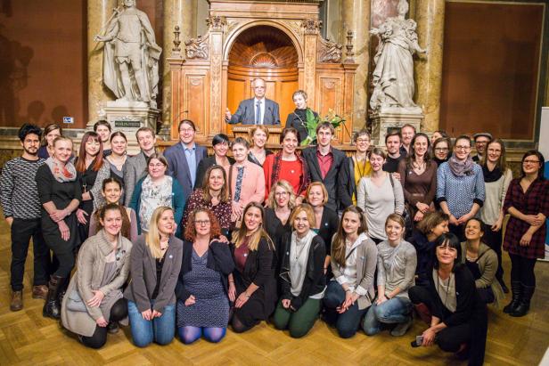 Eine große Gruppe von Menschen posiert in einem Saal mit Statuen für ein Foto.