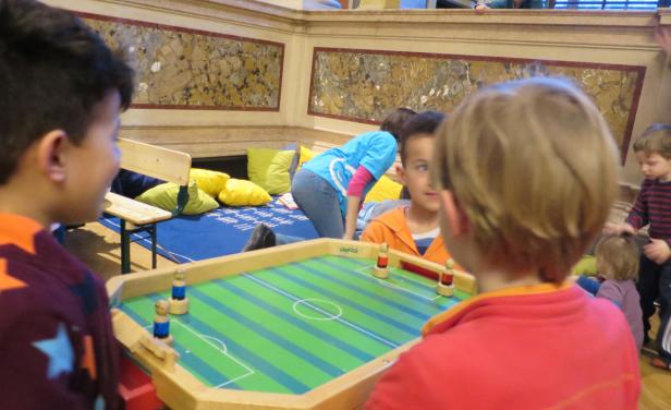 Kinder spielen ein Tischfußballspiel in einem Innenraum.