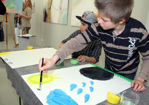 Zwei Jungen malen Bilder mit Farbe auf Papier.