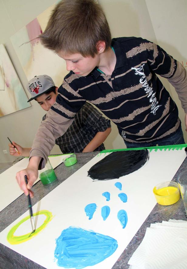 Zwei Jungen malen mit bunten Farben auf Papier.