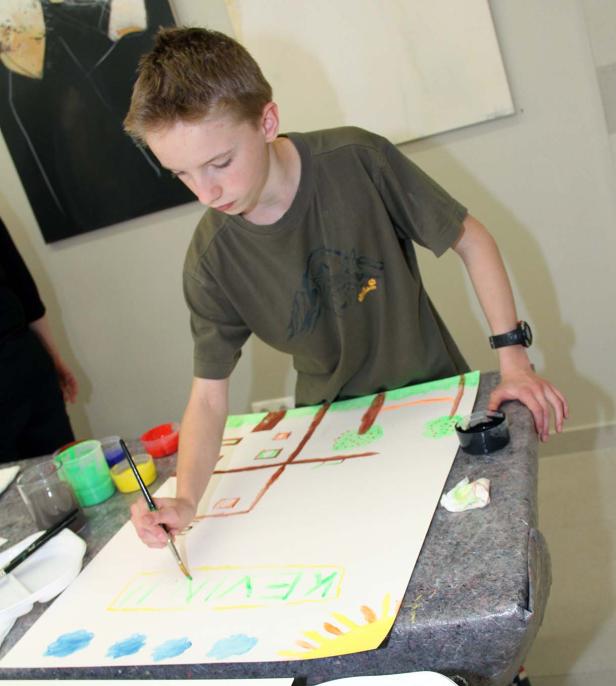 Ein Junge malt ein Bild mit dem Namen „Kevin“ darauf.