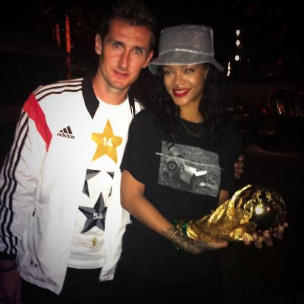 Rihanna hält die FIFA-Weltmeisterschaft-Trophäe mit einem Mann im Deutschland-Trikot.