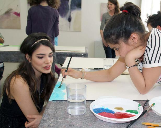 Zwei Mädchen malen mit Wasserfarben auf Papier.