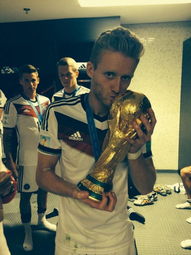 Ein deutscher Fußballspieler küsst den goldenen FIFA-Pokal.