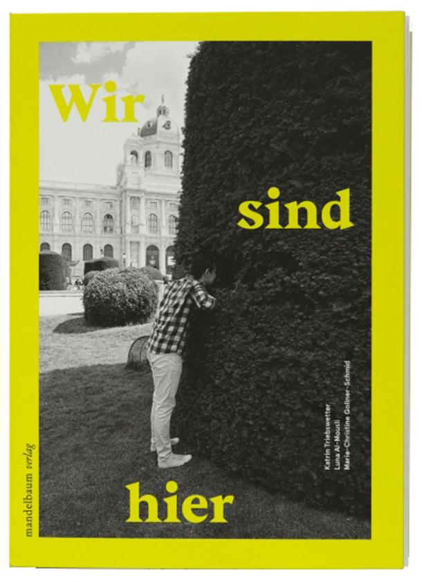 Ein Mann schaut hinter einen großen, geschnittenen Busch vor einem Gebäude in Wien.