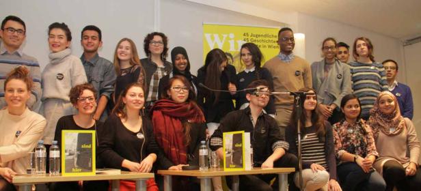 Eine Gruppe junger Menschen posiert für ein Foto mit dem Buch „Wir sind hier“.