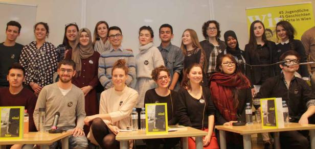 Eine Gruppe junger Menschen posiert für ein Foto vor einem gelben Banner.