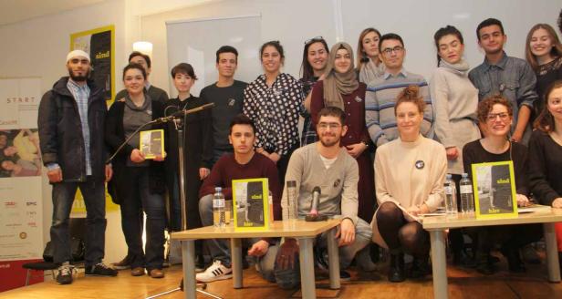 Eine Gruppe junger Menschen posiert für ein Foto mit dem Buch „Sind hier“.