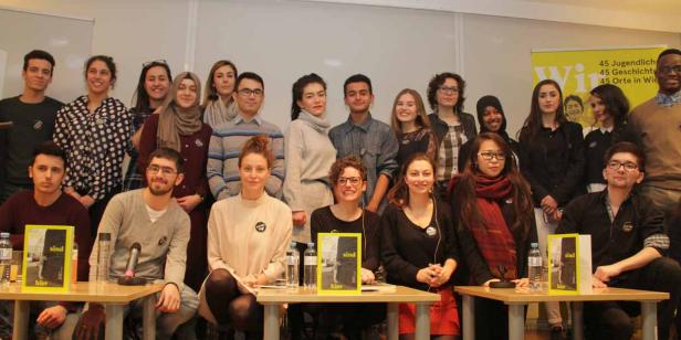 Eine Gruppe junger Menschen posiert für ein Foto vor einem gelben Banner.