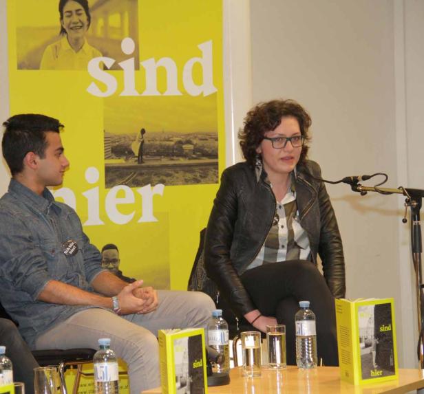 Eine Frau mit Brille spricht bei einer Buchvorstellung von „Wir sind hier“.