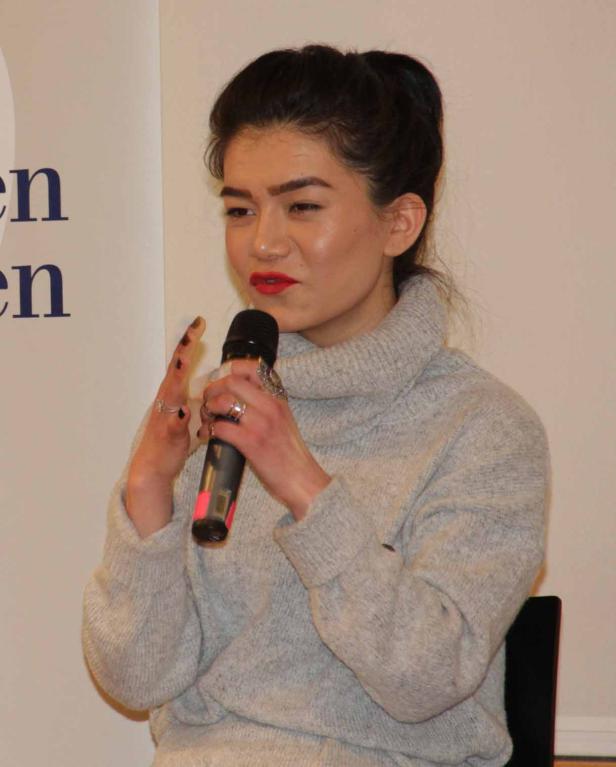 Eine junge Frau spricht in ein Mikrofon.
