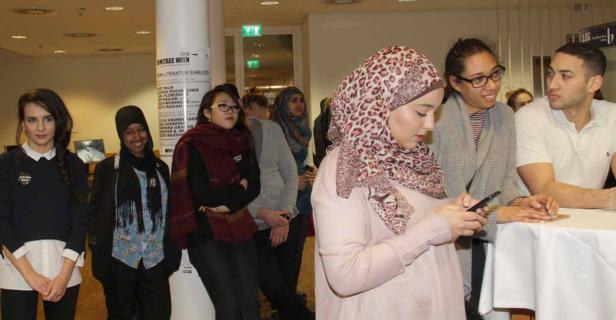 Eine Gruppe junger Menschen steht in einem Raum und unterhält sich.