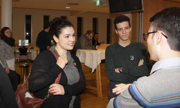 Eine Gruppe junger Leute unterhält sich in einem Raum.