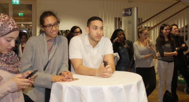 Eine Gruppe junger Menschen steht um einen runden Tisch herum.