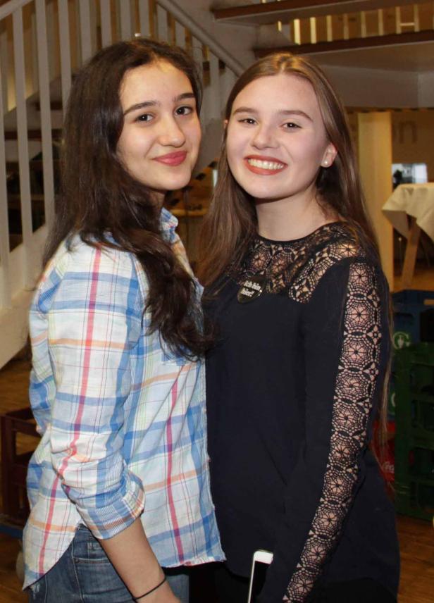 Zwei junge Frauen stehen lächelnd nebeneinander.