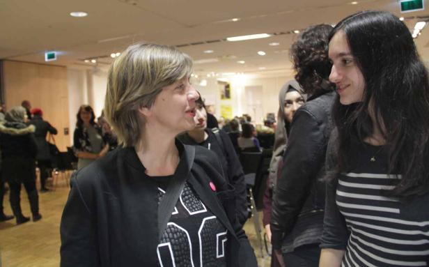 Zwei Frauen unterhalten sich in einem belebten Raum.