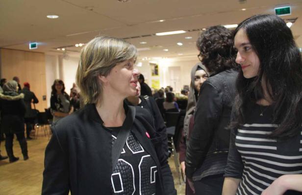 Zwei Frauen unterhalten sich in einem Raum mit anderen Personen.