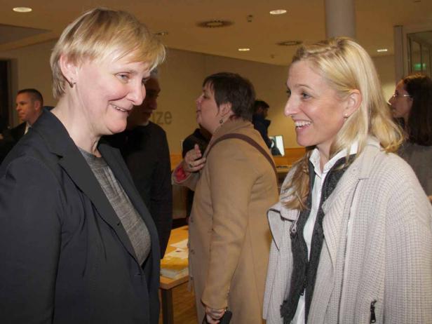 Zwei Frauen unterhalten sich lächelnd in einem Raum.