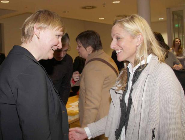 Zwei Frauen unterhalten sich lächelnd in einem Raum.