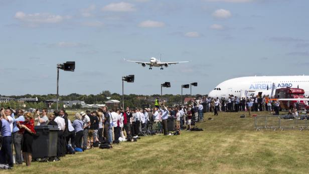 Ein Airbus A380 landet vor einer Menschenmenge auf einem Flugfeld.