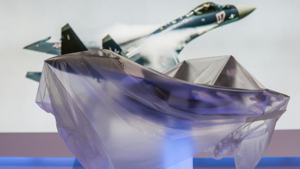 Ein Modell eines Kampfflugzeugs unter einer Plastikplane, im Hintergrund ein weiteres Flugzeug.