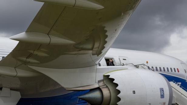 Ein Flugzeug mit einer Stewardess, die aus einer Tür schaut, und einer Rolls Royce Turbine.