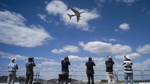 Eine Gruppe von Menschen beobachtet ein Flugzeug am Himmel.