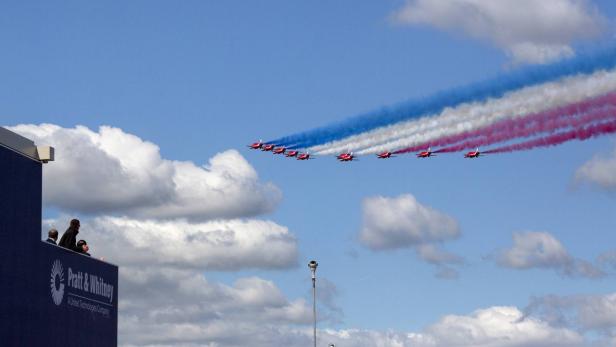 Eine Formation roter Flugzeuge zieht Rauchfahnen in den Farben der britischen Flagge hinter sich her.