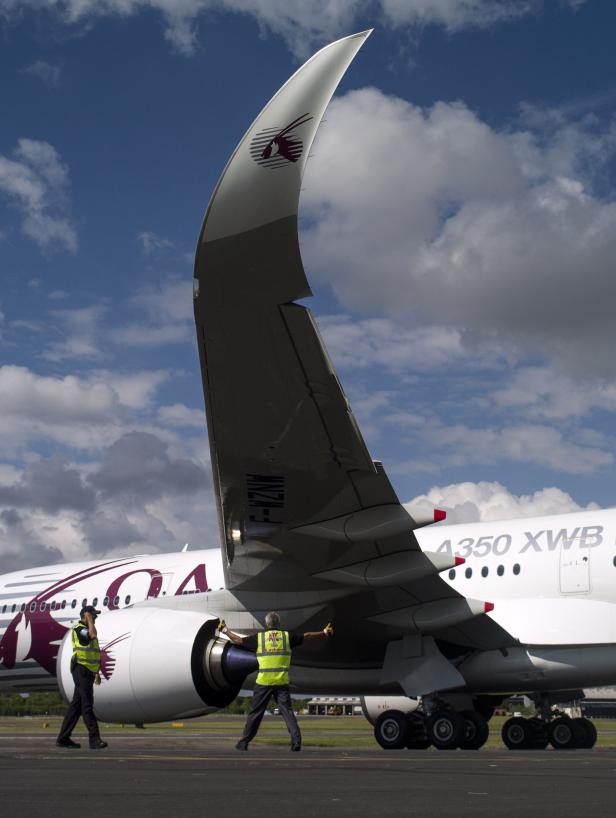 Zwei Arbeiter inspizieren ein Qatar Airways A350 XWB Flugzeug.