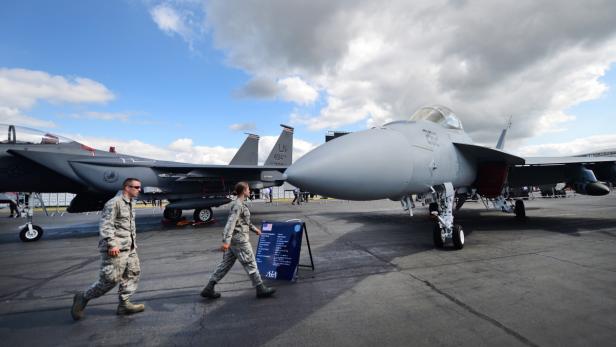 Zwei Militärangehörige gehen an zwei Kampfjets vorbei.