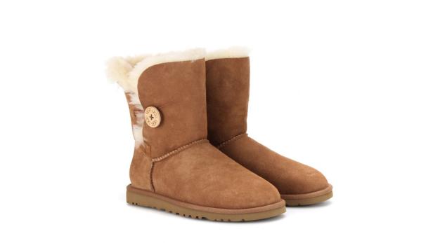 Zwei braune UGG-Boots mit Knöpfen und hellem Fellfutter stehen auf einem weißen Hintergrund.