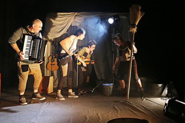 Eine Gruppe von vier Personen tritt mit Akkordeon, Klarinette, Geige und Besen auf einer Bühne auf.