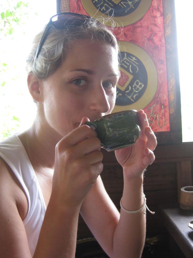 Eine Frau trinkt aus einer verzierten Tasse.