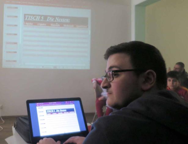 Ein Mann mit Brille sitzt vor einem Laptop, auf dem eine Tabelle mit der Überschrift „Tisch 5 Die Nächsten“ zu sehen ist.