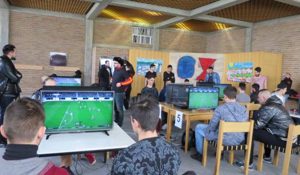 Mehrere Personen spielen ein Fußball-Videospiel auf Computern in einem Raum.