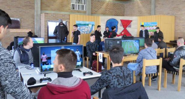 Mehrere Personen spielen ein Fußball-Videospiel auf Computern in einem Raum.