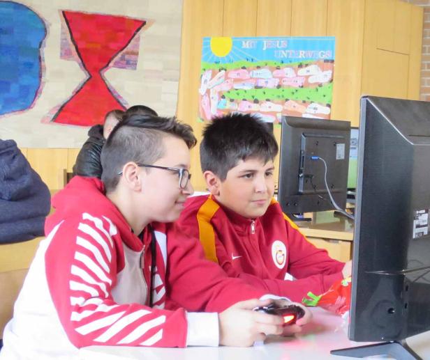 Zwei Jungen spielen zusammen ein Videospiel an einem Computer.