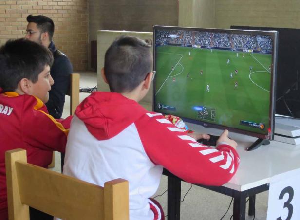 Zwei Jungen spielen ein Fußball-Videospiel auf einem großen Bildschirm.