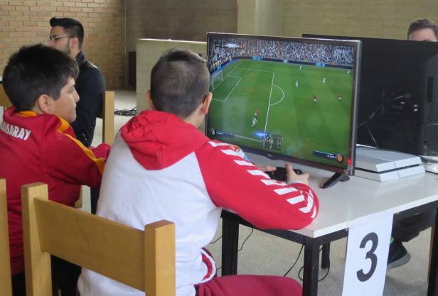 Zwei Jungen spielen ein Fußballvideospiel an einem Tisch mit der Nummer 3.