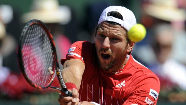 Ein Tennisspieler schlägt einen gelben Tennisball mit seinem Schläger.