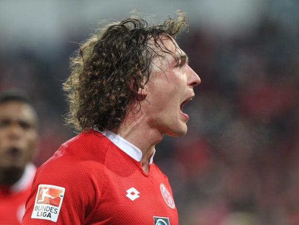 Ein Fußballspieler in rotem Trikot schreit auf dem Spielfeld.