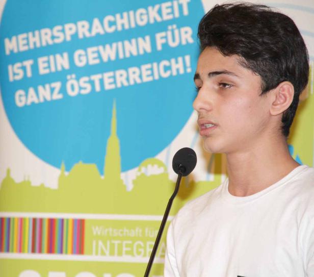 Ein junger Mann spricht bei einer Veranstaltung am Mikrofon.