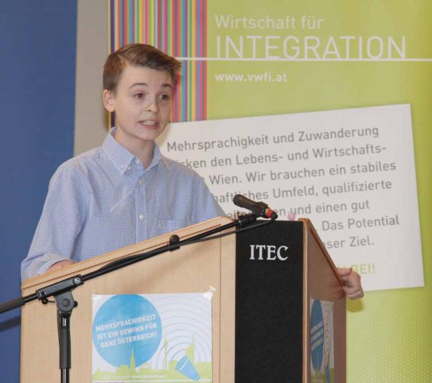 Ein junger Mann hält eine Rede auf einer Veranstaltung von „Wirtschaft für Integration“.
