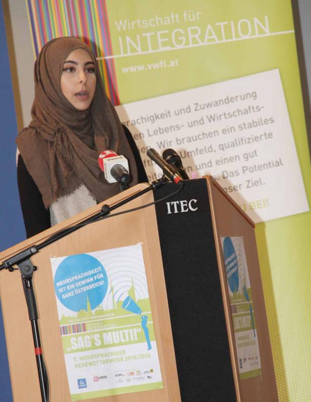 Eine junge Frau mit Kopftuch spricht auf einer Veranstaltung zum Thema Integration.