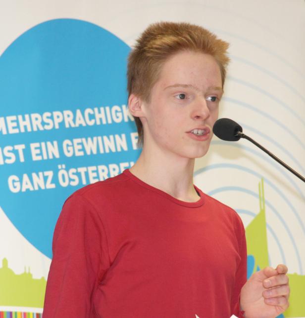 Ein junger Mann spricht bei einer Veranstaltung ins Mikrofon.