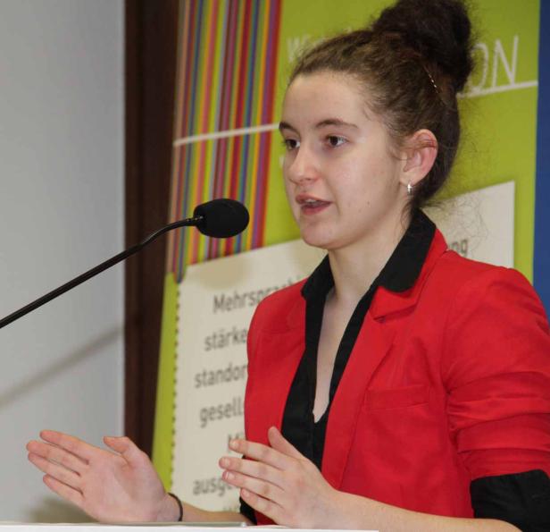 Eine junge Frau hält eine Rede vor einem Mikrofon.