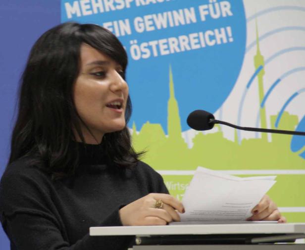 Eine Frau spricht an einem Rednerpult mit Mikrofon vor einem Hintergrund mit der Aufschrift „Mehr Gewinn für Österreich!“.
