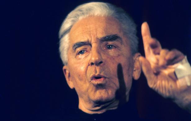 Ein Mann mit grauem Haar gestikuliert mit erhobenem Zeigefinger.